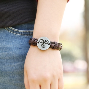 Retro braided leather bracelet with a silver metal triskelion disc on a wrist