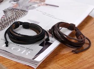 Detail of layered black and dark brown woven leather bracelets with adjustable knots