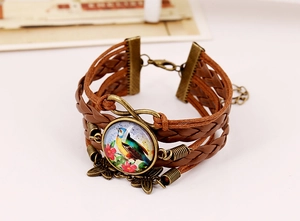 Close-up of vintage multi-layer leather bracelet with infinity charm and bird gem