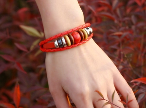 Close-up of a multi-layer red leather braided bracelet with metal and wooden beads on a wrist