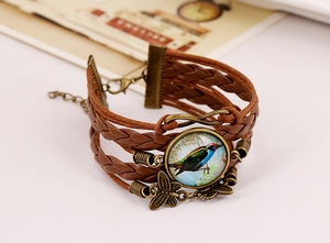 Detailed close-up of multi-layer leather bracelet with bird gem and butterfly charm