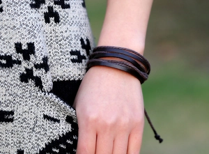 Detail of dark brown multilayer leather bracelet set worn against a cozy knit sweater sleeve