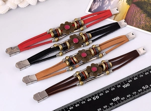 Detail view of multicolored braided leather bracelets with bronze flower charm and beads