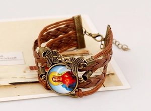 Detailed view of multilayer braided leather bracelet with vintage religious icon and butterfly