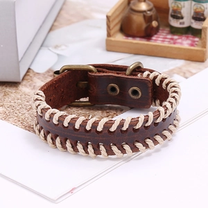 Macro detail of dark brown leather bracelet with cream cross-stitch and vintage buckle