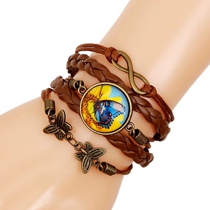 Detail of vintage multilayer braided bracelet with butterfly pendant and blue glass charm
