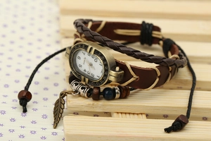 Macro detail of retro leather wrap watch with bronze leaf charm and wooden beads