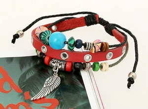 Detail of red leather multilayered beaded bracelet with a silver feather charm and cord