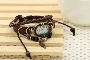 Detail of vintage leather bracelet watch with bronze leaf pendant and woven straps