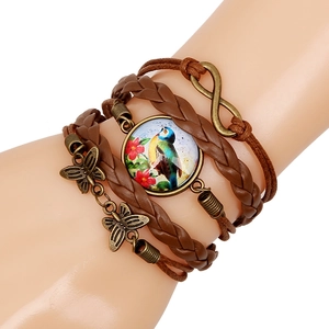 Macro view of multi-layer leather bracelet featuring Kingfisher glass gem and butterfly charms