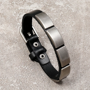Detail of a black leather punk bracelet with five antique silver metal plates and buckle