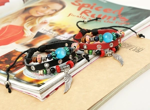 Detail of red and black leather bohemian multi-layer bracelet with wing charm and beads