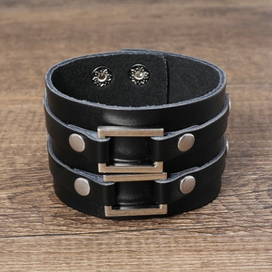 Detail of punk wide leather bracelet with silver metal buckles and studs on wood