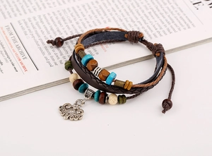 Detail of multi-layer boho leather bracelet with beads and metal pendant on magazine