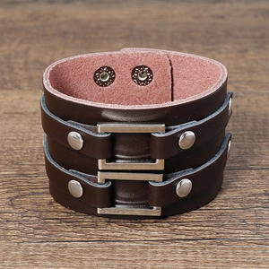 Detail of wide dark brown leather cuff bracelet with silver square studs and metal snaps