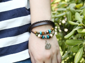 Detail of bohemian multilayer leather bracelet with vintage floral charm and beads