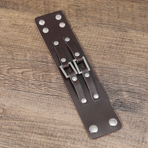 Detail of wide brown leather biker bracelet with silver metal studs and square buckles