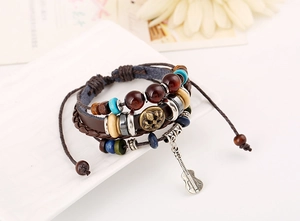 Detail of multi-layer leather bracelet with guitar charm and vintage beads on white plate