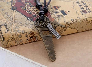 Close-up of vintage industrial necklace featuring bronze key, cross, and engraved plate