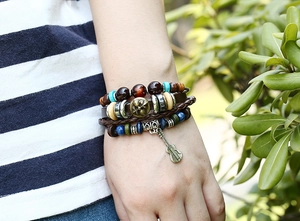Detail of layered leather bracelet with guitar charm and tiger eye beads on wrist