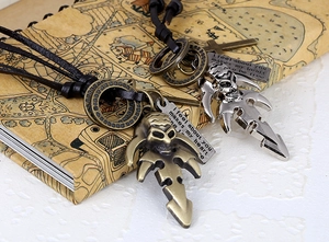 Detail of vintage leather necklaces with skull and cross charms on an old map background