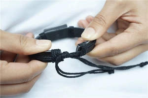 Detail of black woven leather bracelet with adjustable pull-string knot closure