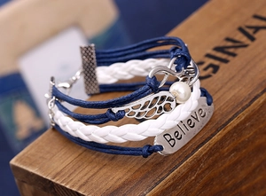 Detail of multi-layer woven bracelet featuring Believe charm, wings and infinity symbols