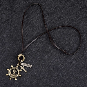 Detail of adjustable leather cord necklace with vintage bronze rudder and cross charms