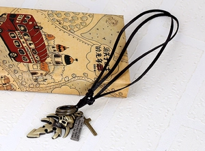 Macro detail of bronze skull and cross charms on a black leather vintage necklace