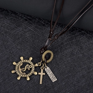 Macro detail of nautical rudder pendant with cross and engraved metal tag on leather cord