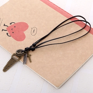Retro black leather necklace for men featuring bronze saw and cross pendants on a notebook