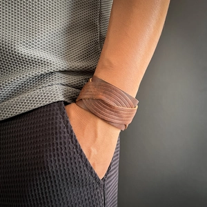 Gros plan d'un bracelet multicouche en cuir marron tressé sur un poignet d'homme