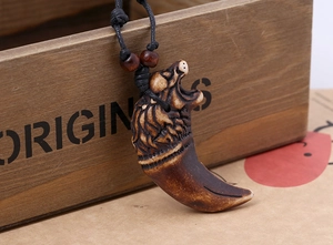 Detail of hand-carved eagle head and faux wolf tooth pendant on a rustic woven cord