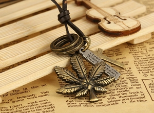 Macro detail of vintage bronze maple leaf and cross pendants on leather cord necklace