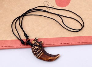 Detailed view of tribal wolf head pendant on black wax cord with wooden beads