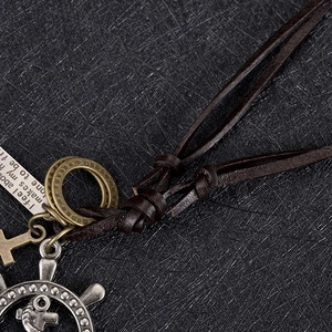 Detail of vintage leather necklace with rudder, cross, and engraved metal tag charms