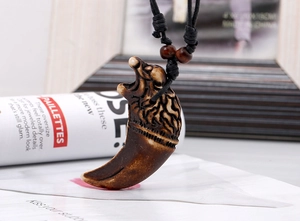Detailed close-up of resin wolf fang pendant with eagle head carving and black cord