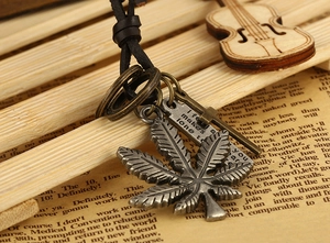Macro shot of vintage silver maple leaf pendant with cross and black leather cord