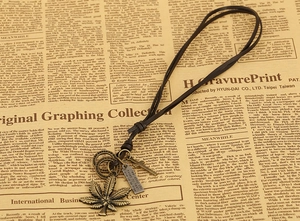 Detailed macro view of vintage bronze maple leaf and cross pendants on leather cord