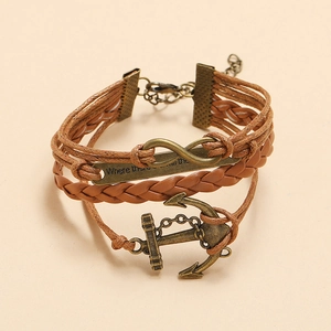 Detail of vintage braided leather bracelet with infinity symbol and anchor charms