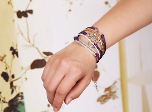 Détail d'un bracelet en cuir tressé avec breloque vélo et plaque à citation gravée
