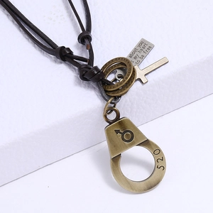 Detail of vintage bronze handcuffs and cross charms on a brown leather necklace