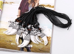 Detail of tribal eagle pattern on resin tooth pendant necklace with wooden beads