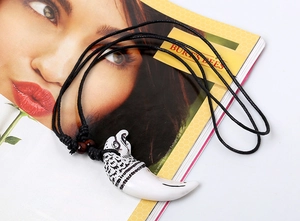 Detail of eagle head resin tooth pendant necklace with woven wax cord and beads