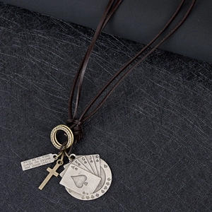 Détail d'un collier en cuir vintage avec croix et cartes de poker sur fond noir