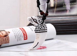 Detail view of ethnic eagle head pendant with resin fang on black woven cord