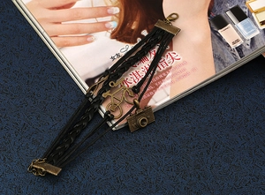 Détail macro du bracelet en cuir tressé avec breloques rétro en forme de vélo et appareil