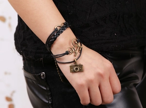 Détail d'un bracelet en cuir multicouche avec pendentifs appareil photo et vélo