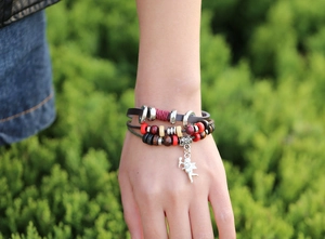Gros plan d'un bracelet vintage multicouche en cuir avec perles en bois et breloque Cupidon