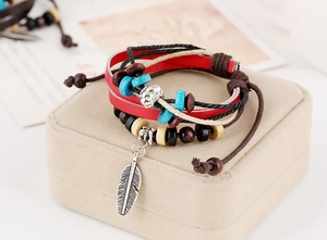 Close-up of bohemian leather bracelet with turquoise beads and a silver feather charm